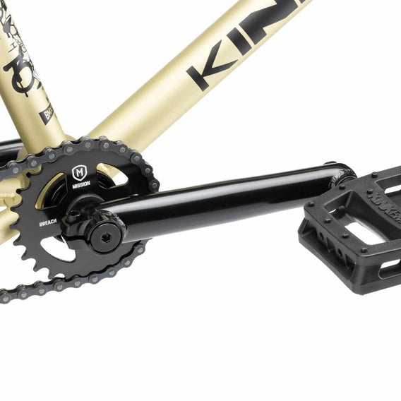 Close up of drive chain on Kink Curb BMX bike in desert gold, photo shows Mission Breach 25 tooth sprocket, Mission Triumph Chromoly 3 piece cranks and Kink Hemlock plastic pedal