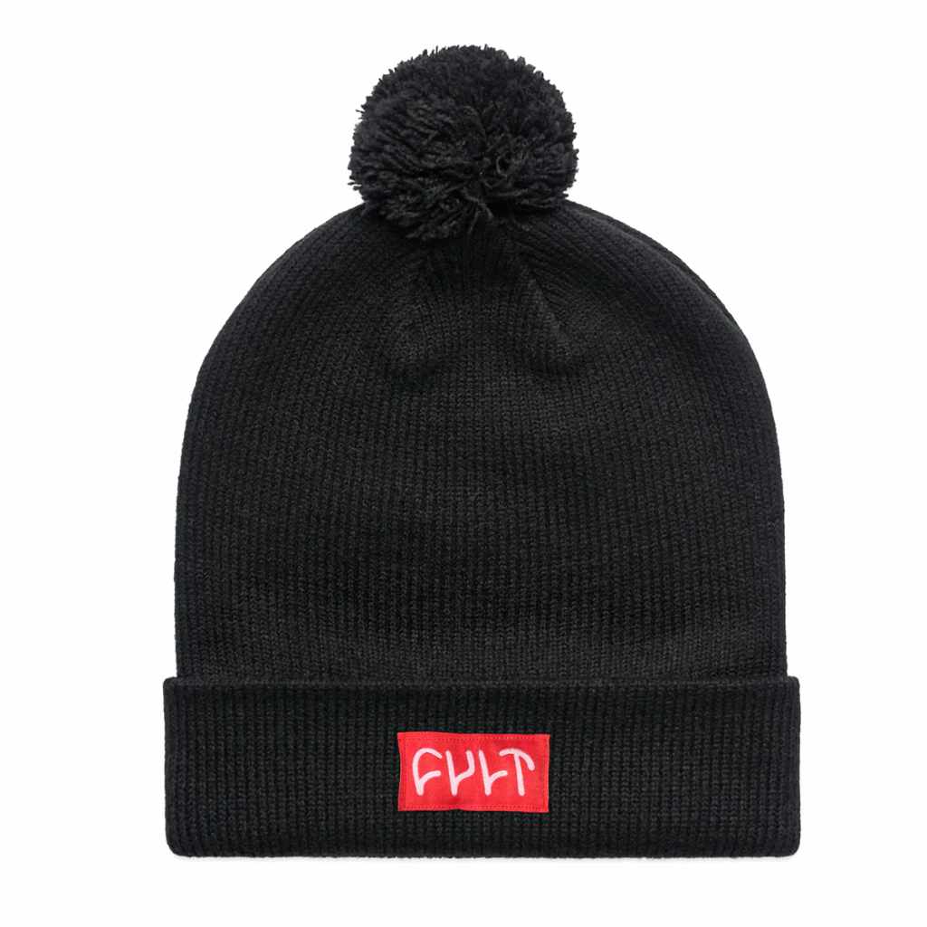 Black Cult beanie made with tightly ribbed acrylic with a Pom Pom on the top. The beanie is folded at the bottom and shows a red sewn on patch with a white Cult logo on it.