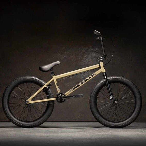 Kink Curb 20 inch BMX bike in desert gold photographed from the side in an industrial warehouse