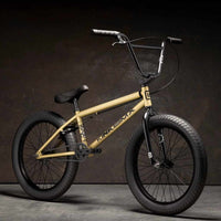 Kink Curb 20 inch BMX bike in desert gold photographed at a 45 degree angle in an industrial warehouse