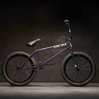 Side view of Kink Downside 20 inch BMX bike in hazy purple photographed in an industrial warehouse