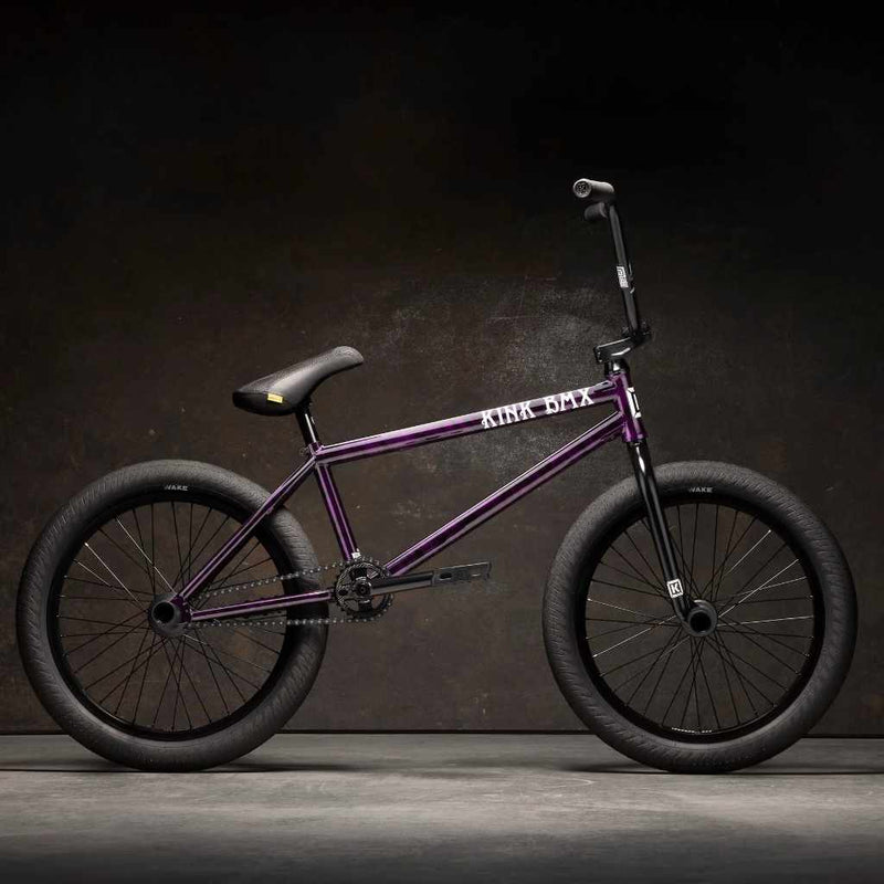 Side view of Kink Downside 20 inch BMX bike in hazy purple photographed in an industrial warehouse