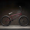Side view of Kink Launch 20 inch BMX bike in plasma red photographed in an industrial warehouse
