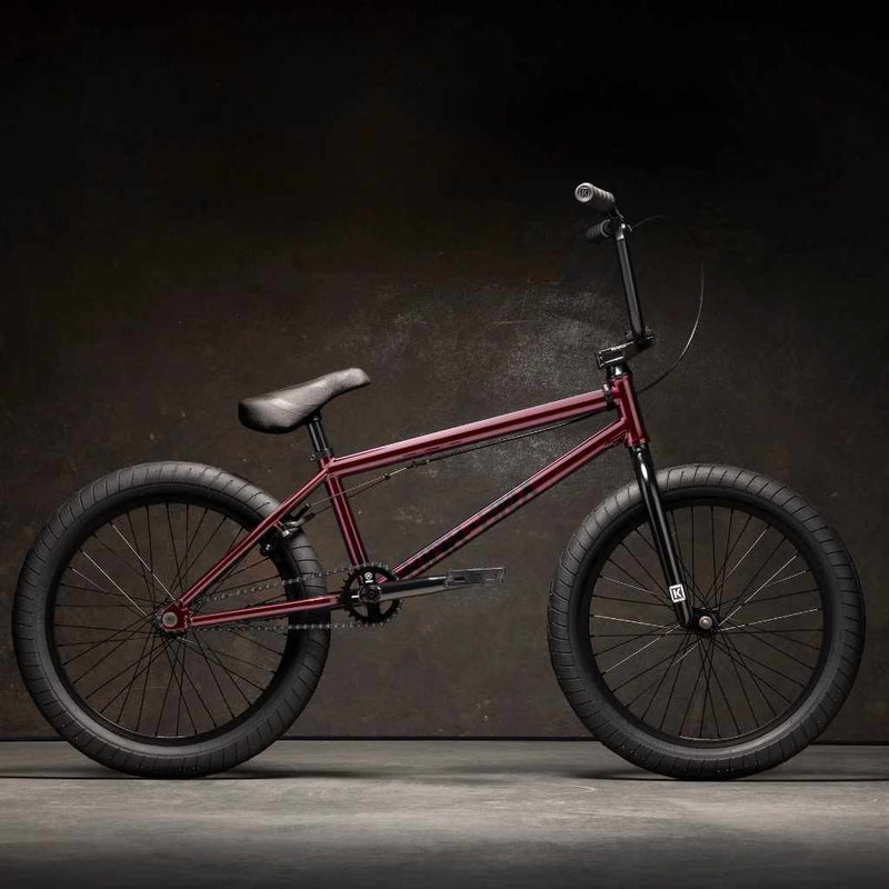 Side view of Kink Launch 20 inch BMX bike in plasma red photographed in an industrial warehouse