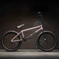 Side view of Kink Launch 20 inch BMX bike in platinum rose photographed in an industrial warehouse