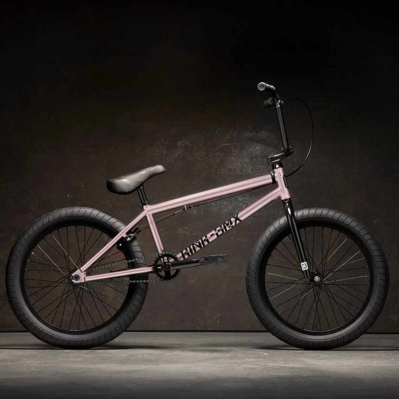 Side view of Kink Launch 20 inch BMX bike in platinum rose photographed in an industrial warehouse