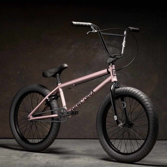 Kink Launch 20 inch BMX bike in platinum rose photographed at a 45 degree angle in an industrial warehouse