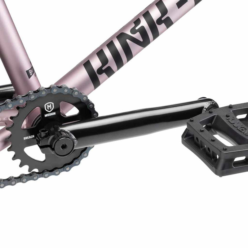 Close up of drive chain on Kink Launch BMX bike in platinum rose, photo shows Mission Breach 25 tooth sprocket, Mission Triumph Chromoly 3 piece cranks and Kink Hemlock plastic pedal
