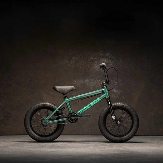 Kink Pump 14" BMX bike in Green side view, photographed in an industrial warehouse