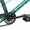 Close up photo of the Kink Pump 14" drive train. This shows the black Mission Rank 25 tooth sprocket,  one piece cranks and black plastic pedals against the green frame