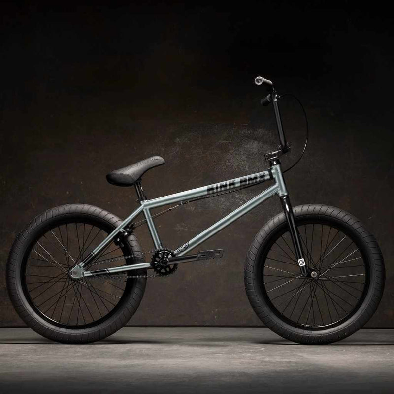 Side view of Kink Whip 20 inch BMX bike in slate grey photographed in an industrial warehouse