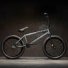 Side view of Kink Whip XL 20 inch BMX bike in slate grey photographed in an industrial warehouse