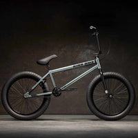 Side view of Kink Whip XL 20 inch BMX bike in slate grey photographed in an industrial warehouse