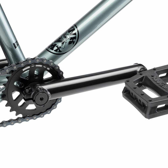 Close up of drive chain on Kink Whip XL BMX bike in slate grey, photo shows Mission Charge 25 tooth sprocket, Mission Triumph Chromoly 3 piece cranks and Kink Hemlock plastic pedal