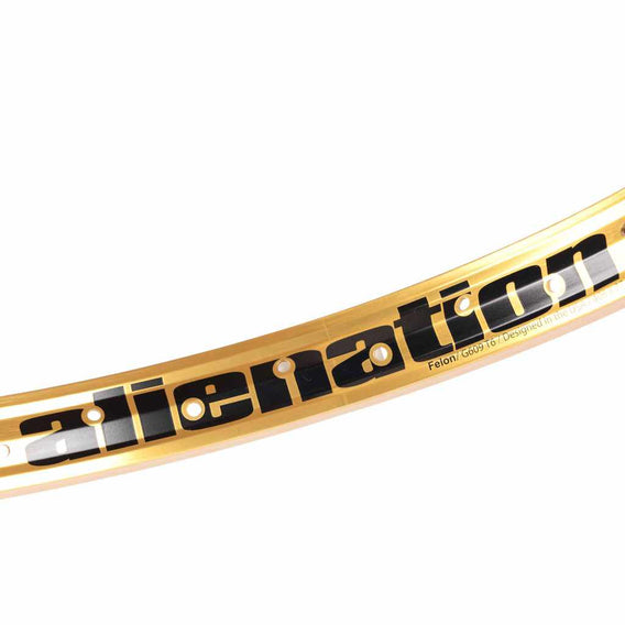 Close up of a Gold Alienation TCS Felon rim showing the Alienation graphic photographed on a white background