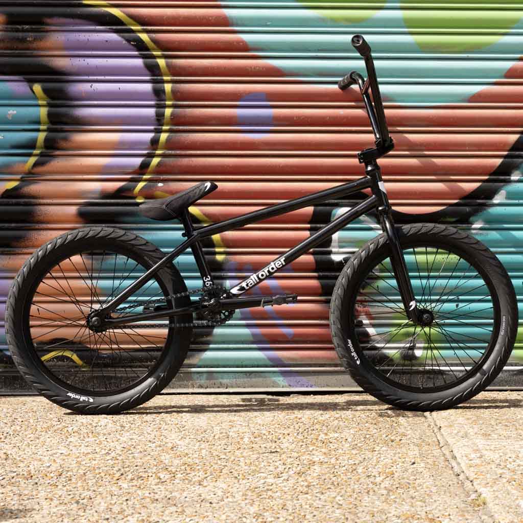 Black bicycle leaning against a colorful graffiti-covered wall. Tall Order 360 Bike - Black 21"
