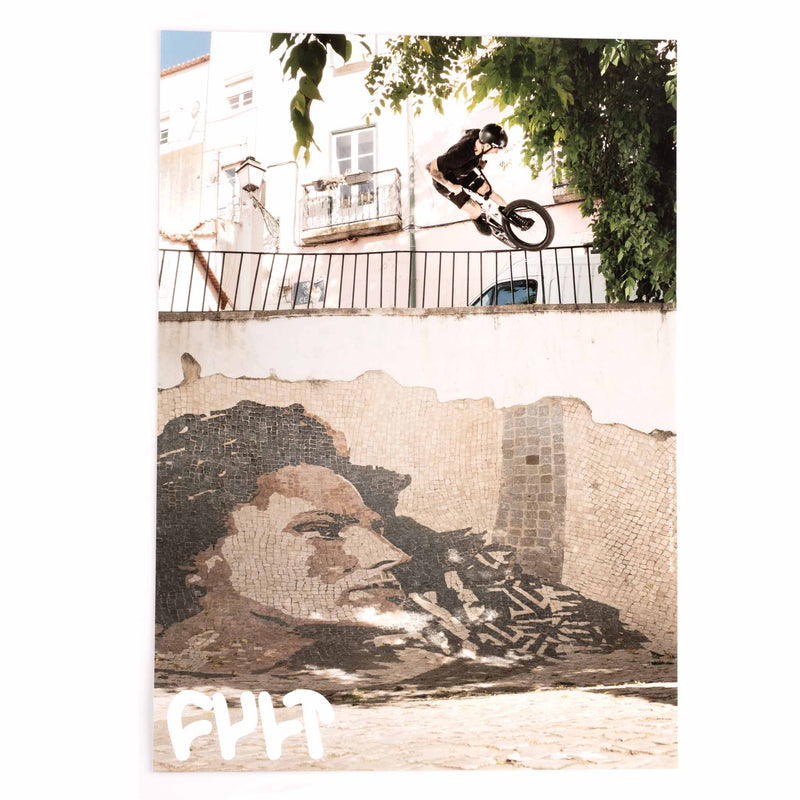 Person on a bicycle performing a trick above a mural of a woman with a camera.