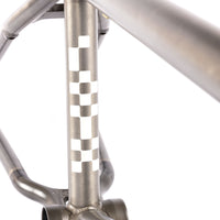Close-up of a metallic bike frame with a checkered pattern on a white background
