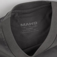Close-up of a gray shirt with 'MAHD' branding and size label.