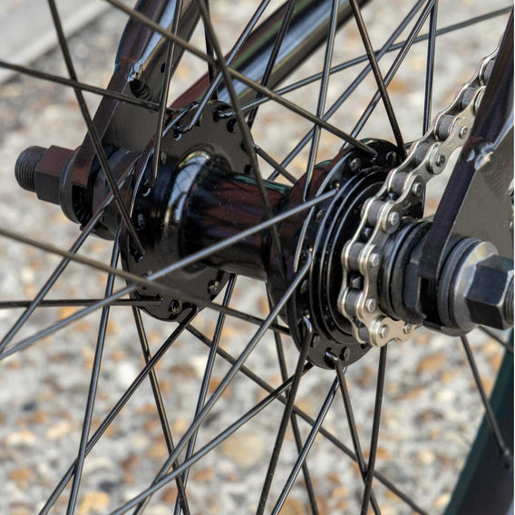 Close-up of a bicycle wheel with chain and gear mechanism on a blurred background