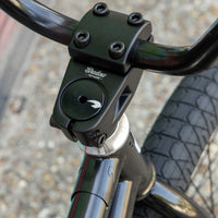 Close-up of a bicycle handlebar with 'Shadow Conspiracy' branding on a blurred background.