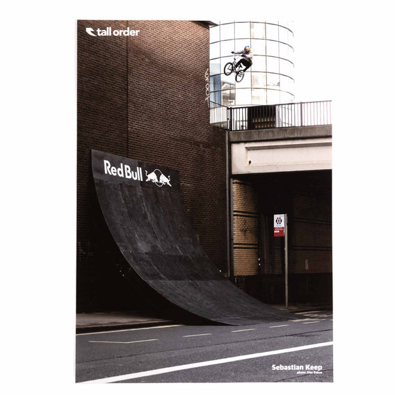 Sebastian Keep performing a trick on a ramp with 'Red Bull' and 'Tall Order' logos.