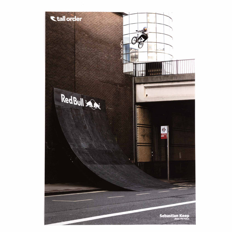 Sebastian Keep performing a trick on a ramp with 'Red Bull' and 'Tall Order' logos.