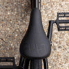 Close-up of a black cult bmx seat with a textured surface on a gravel background