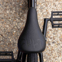 Close-up of a black cult bmx seat with a textured surface on a gravel background